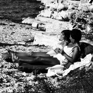 Black and white photo of people relaxing by the sea.