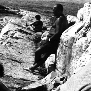 People relaxing on rocky coastline near the water.
