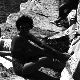 People relaxing on rocky coastline near the water.