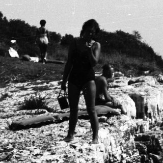 People relax and pose on a rocky coastline.