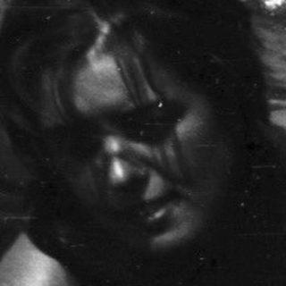 Woman submerged in water, rocky background visible.