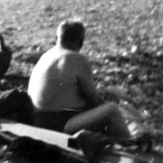 Black and white photo depicts people on a beach path.