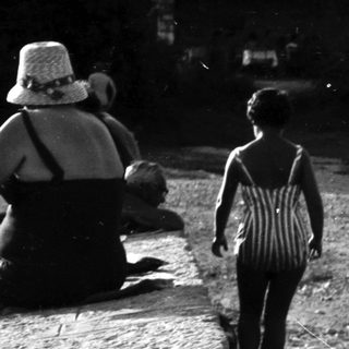 Black and white photo depicts people on a beach path.