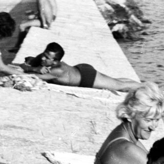 People sunbathing and relaxing on a concrete seaside wall.