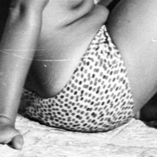 Here's a brief summary: Two women in swimwear relax by the water's edge.
