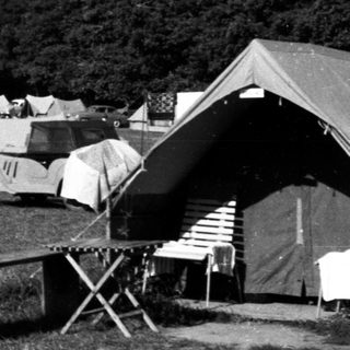 Black and white image of a vintage campsite with vehicles.