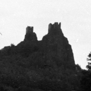 Ruined castle on hill, grassy field, solitary tree.