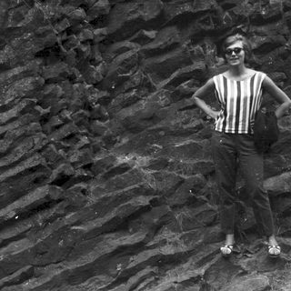 Woman posing near layered rock formation in black and white.
