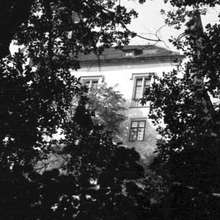 Building partially visible through trees in a dark scene.