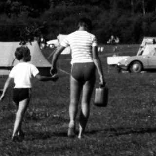 Black and white image of people at a campsite.