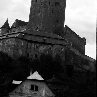 Towering castle looms over a smaller, weathered building.