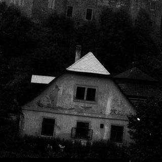 Towering castle looms over a smaller, weathered building.
