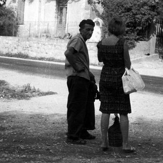 Man and woman conversing on a dusty road.