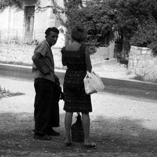 Man and woman conversing on a dusty road.