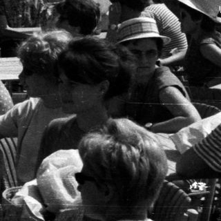 Group of people gathered outdoors near a body of water.