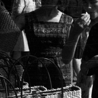 Black and white photo depicts people at a market stall.