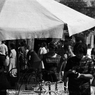 Black and white photo depicts people at a market stall.
