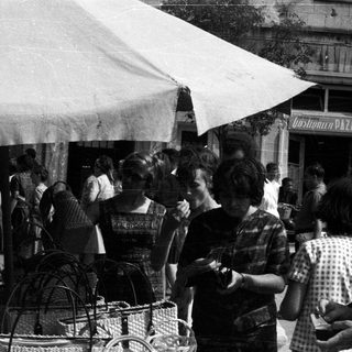 Black and white photo depicts people at a market stall.