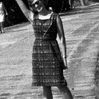 Woman waving on a rural road in a vintage scene.