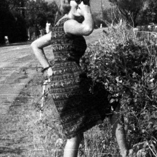 Woman in dress running along a roadside.