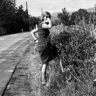 Woman in dress running along a roadside.
