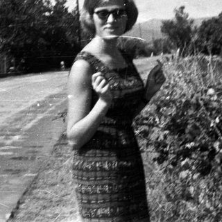Woman in a dress stands on a rural road.