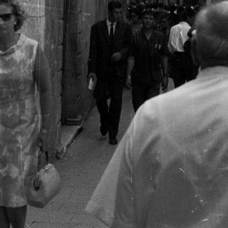 Black and white photo of people in a narrow, old street.