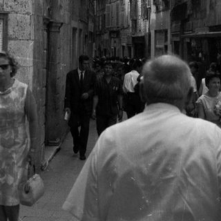 Black and white photo of people in a narrow, old street.