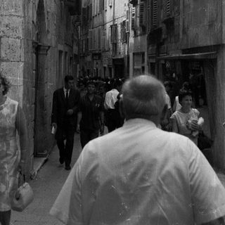Black and white photo of people in a narrow, old street.