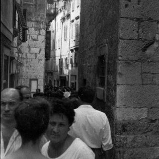 Black and white image of people in a narrow, old street.