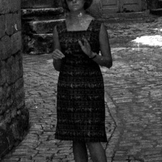 Woman stands in a narrow, old stone alleyway.