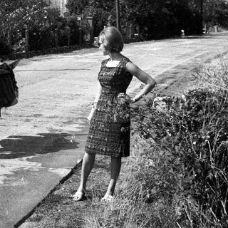 Woman and donkey walking down a rural road.