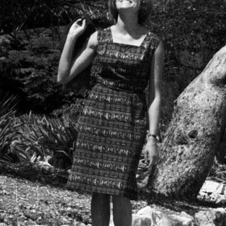 Woman stands near a tree in a tropical garden.