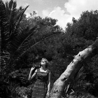 Woman stands near a tree in a tropical garden.