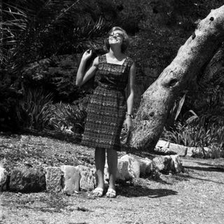 Woman stands near a tree in a tropical garden.