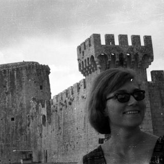 Woman poses in front of a historic castle wall.