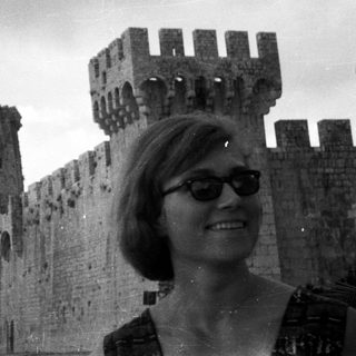 Woman poses in front of a historic castle wall.