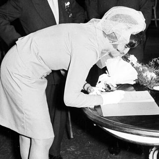 Woman signs a document, accompanied by men.