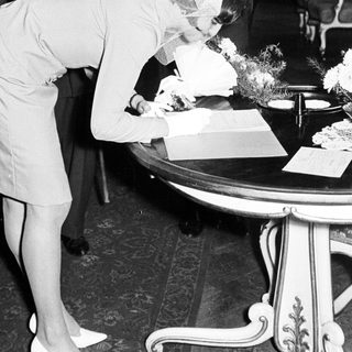 Woman signs a document, accompanied by men.