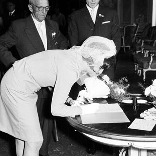 Woman signs a document, accompanied by men.