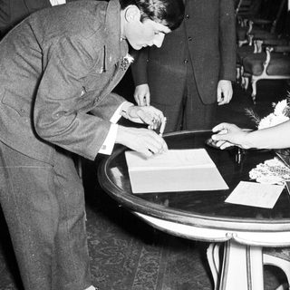 Man signing a document, flanked by two men.