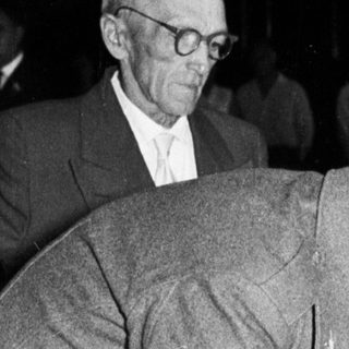 Man signing a document, flanked by two men.