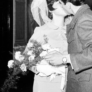 Couple kissing at a wedding, surrounded by guests.