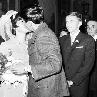Couple kissing at a wedding, surrounded by guests.