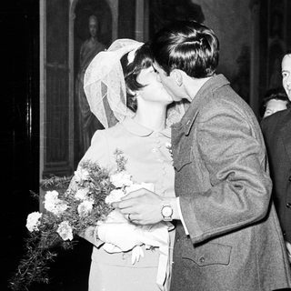 Couple kissing at a wedding, surrounded by guests.