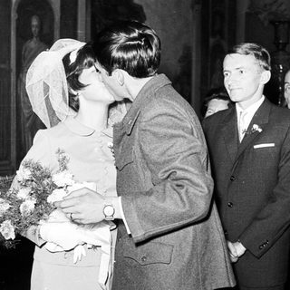 Couple kissing at a wedding, surrounded by guests.