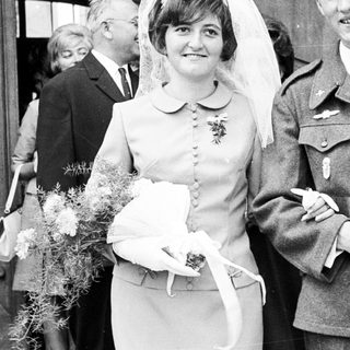 Couple in military uniform and wedding dress pose for photo.