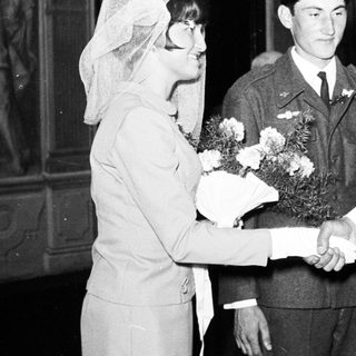 Bride greets military officer and man in a suit.