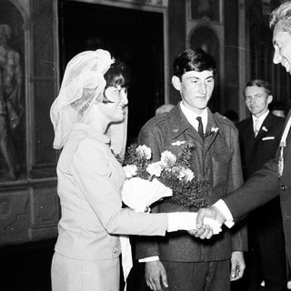 Bride greets military officer and man in a suit.