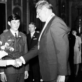 Bride greets military officer and man in a suit.